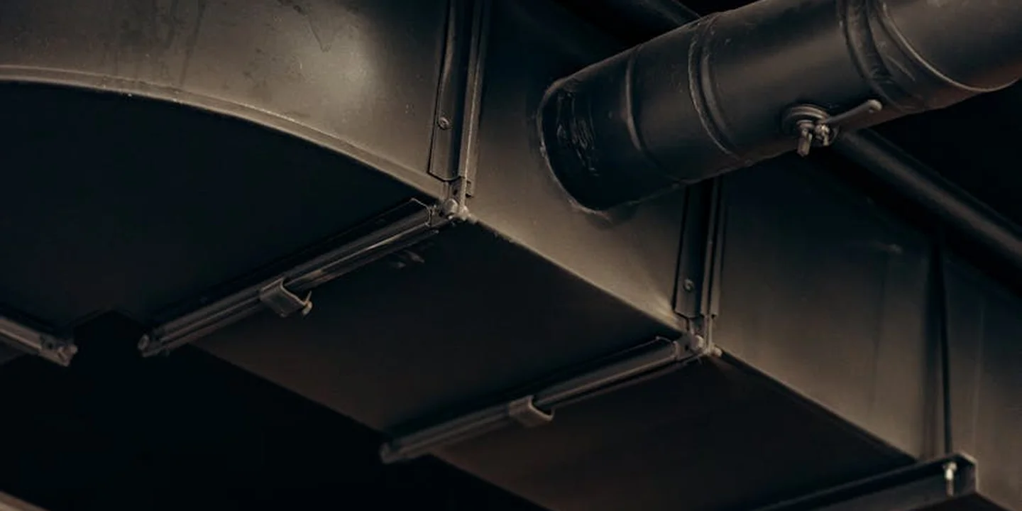 Close-up view of metal ducts and piping in an attic ceiling