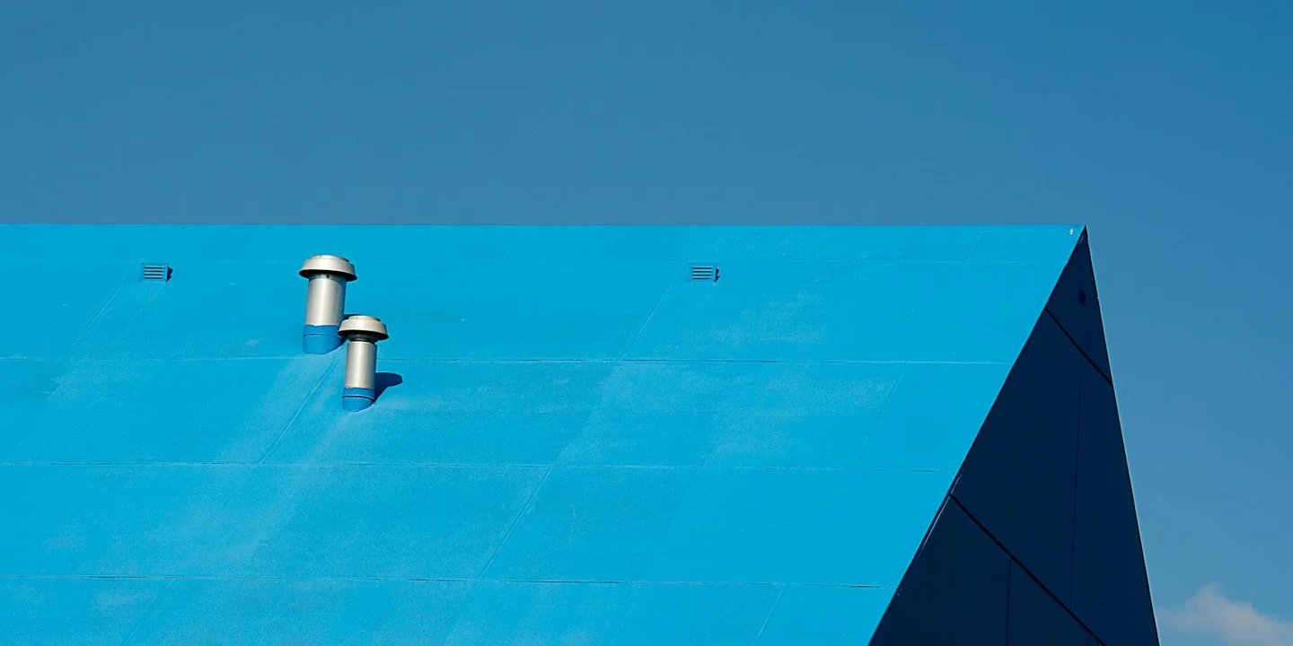 Blue roof with two metal roof vents on a bright day, illustrating roof ventilation.