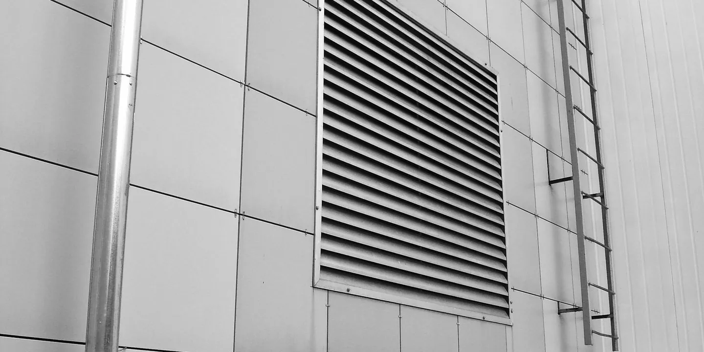 Exterior metal-clad wall with a large rectangular louver vent.