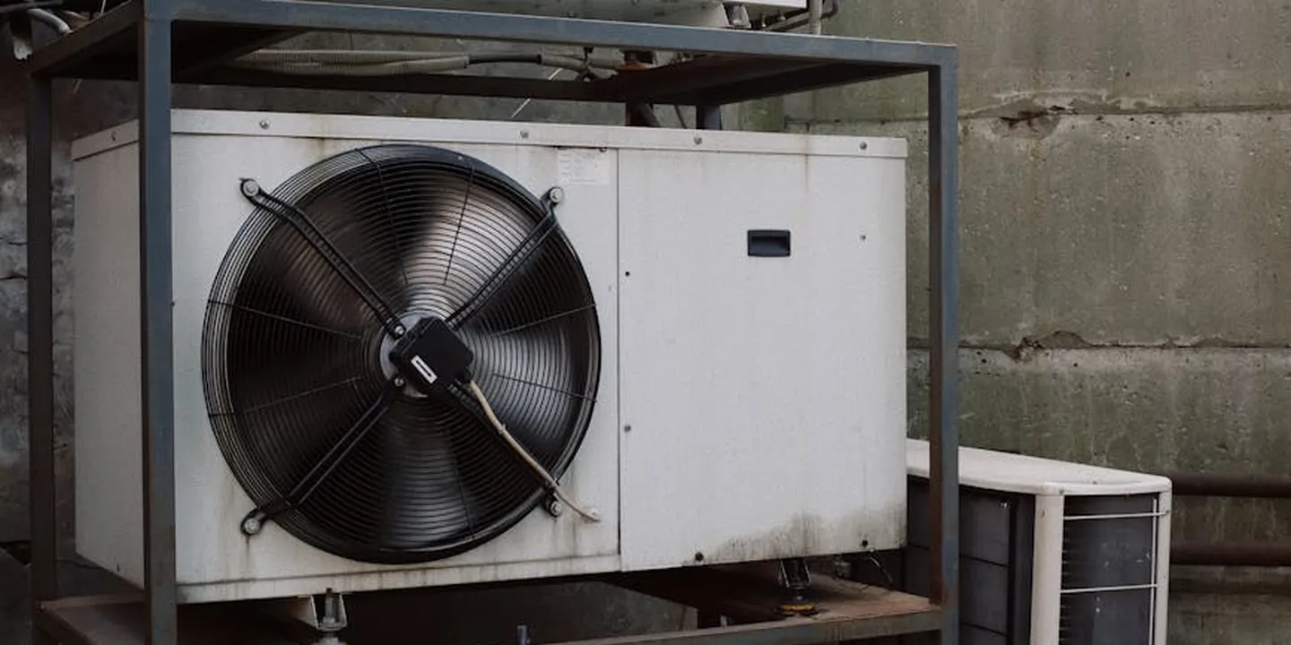 Large industrial outdoor ventilation fan mounted in a metal frame against a concrete wall.
