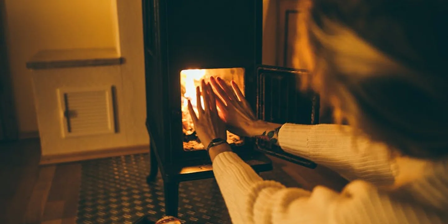 Hands reaching toward a lit fireplace, warm glow filling the room