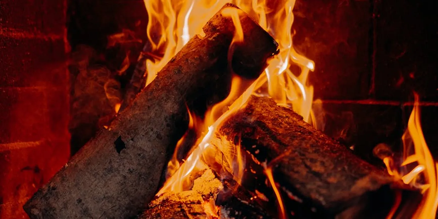 Close-up of a burning wood fire in a brick fireplace, illustrating chimney draft considerations and the role of a draft inducer in venting.