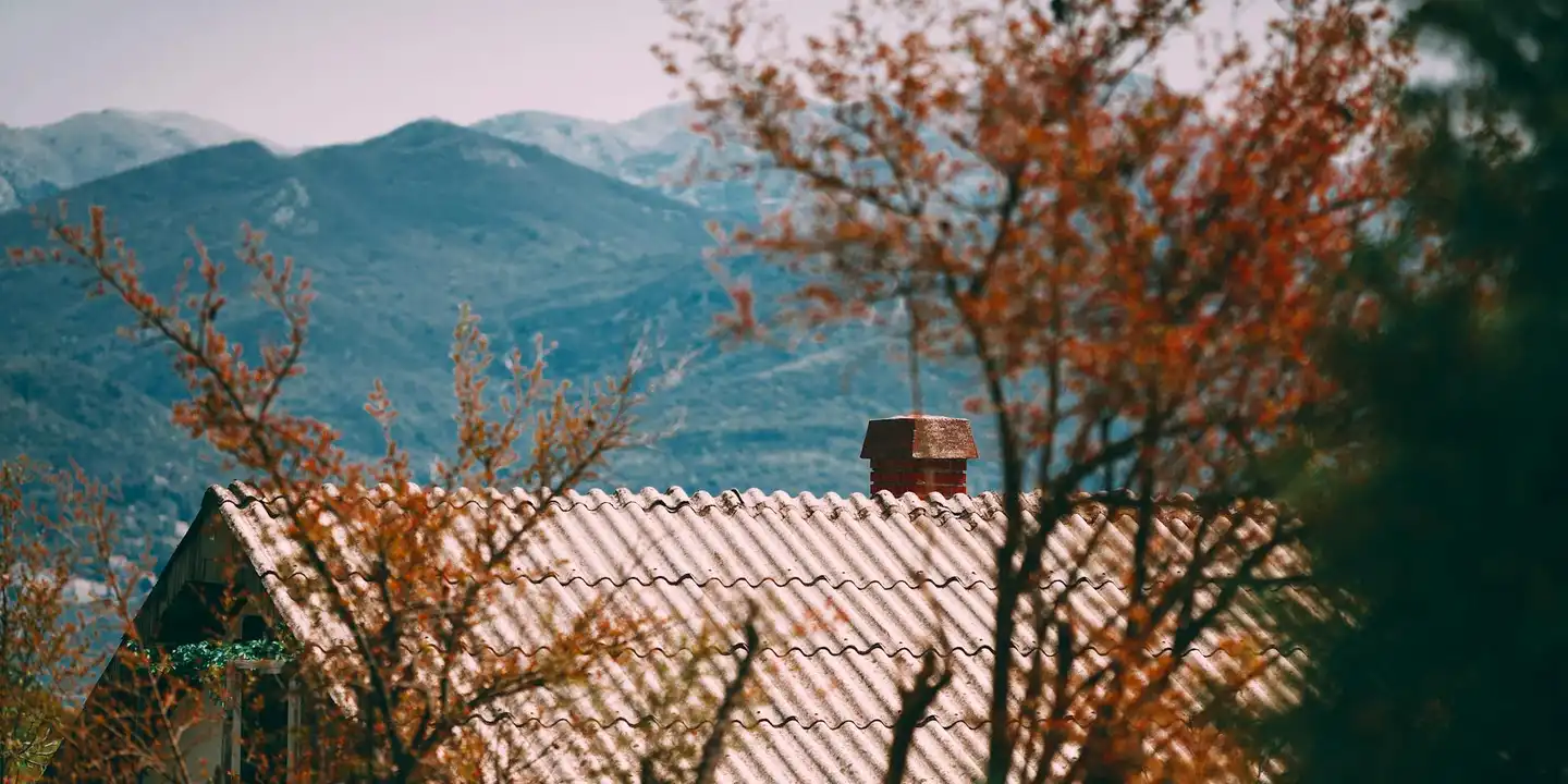 Chimney on a tiled roof with a mountain landscape in the background, illustrating masonry repair materials.
