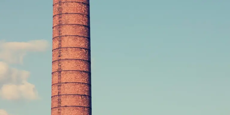 Brick chimney stack with a bright blue sky in the background
