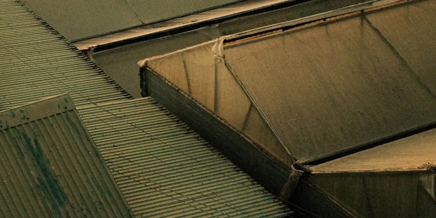 Close-up of a flat metal roof with intersecting seams and flashing, illustrating potential leak points