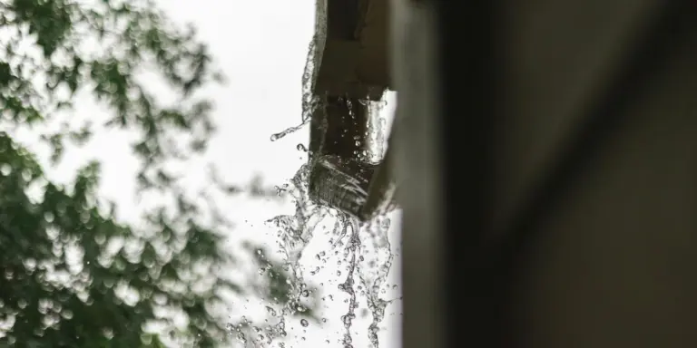 Close-up of water spilling from a gutter during rain, highlighting overflow
