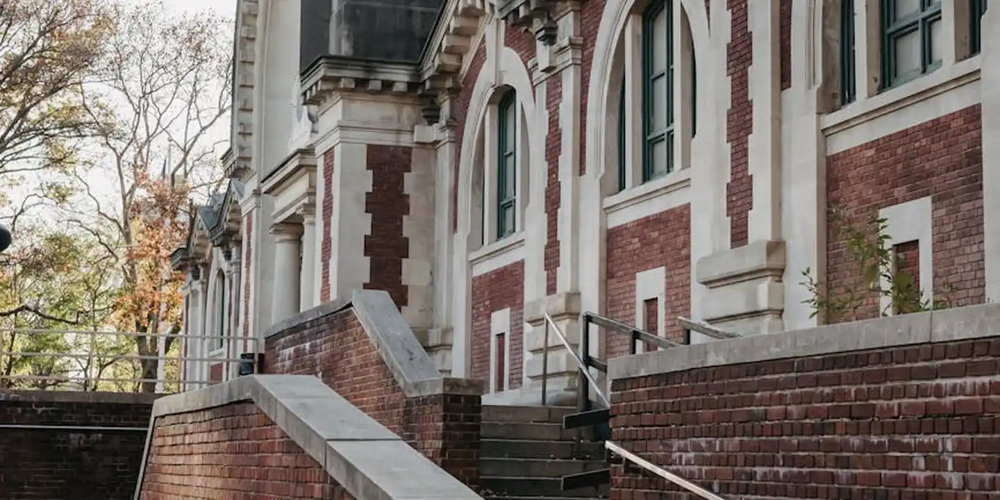 Exterior of a historic brick building with white stone trim, arched windows, and a brick staircase.
