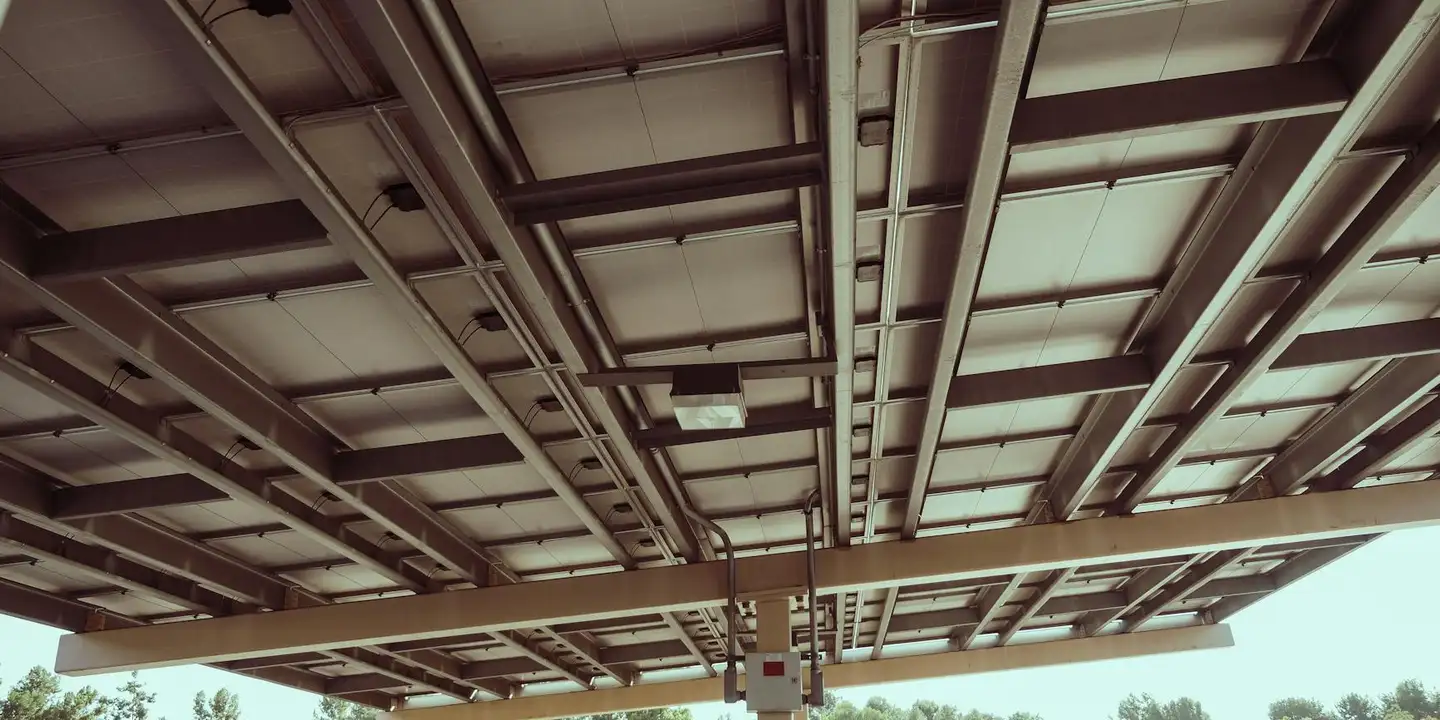 Underside view of metal roofing panels and supporting framework, showing the grid of support beams and panel joints.