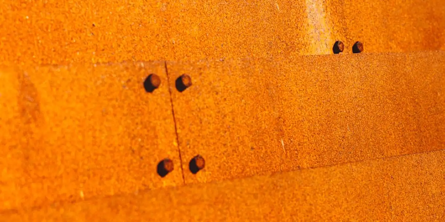 Close-up of orange rusted metal roofing panels with rivet holes