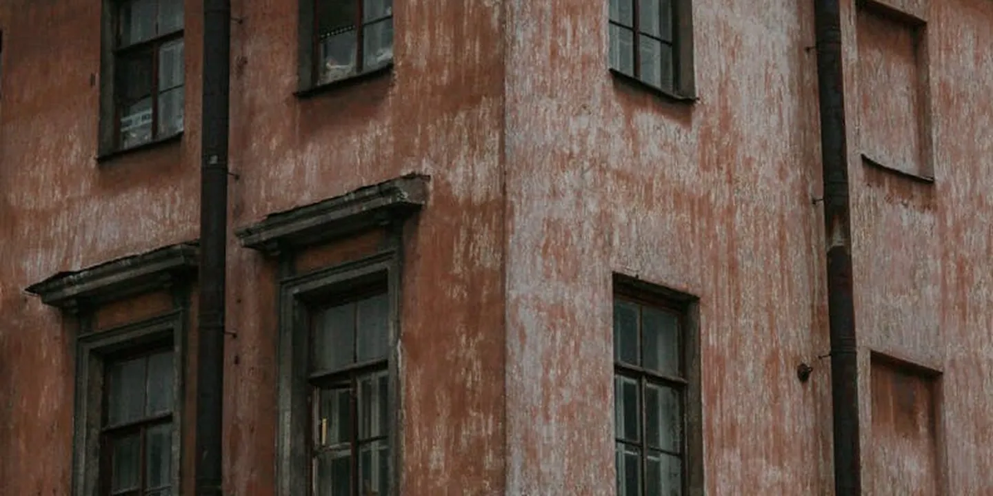Weathered orange wall with multiple windows, illustrating the complexity of building facades and potential gutter routing challenges.