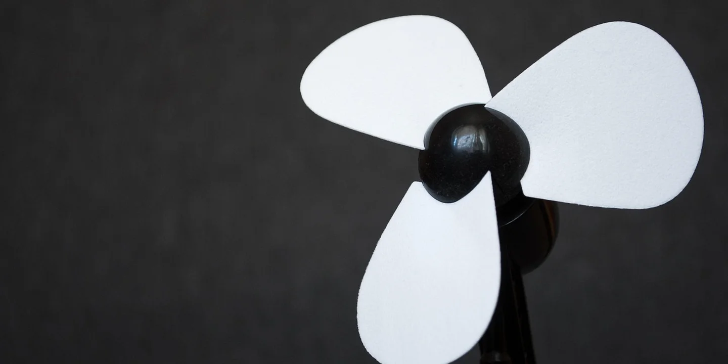 Three white roof turbine vent blades with a black center against a dark background