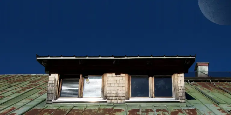 Roof with dormer windows and a green metal roof, illustrating architectural details relevant to gutter profiles
