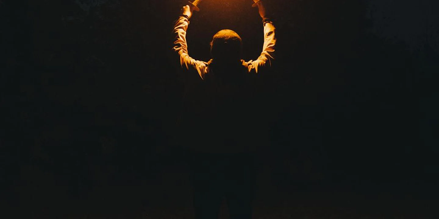 Silhouette of a worker holding a torch against a dark background