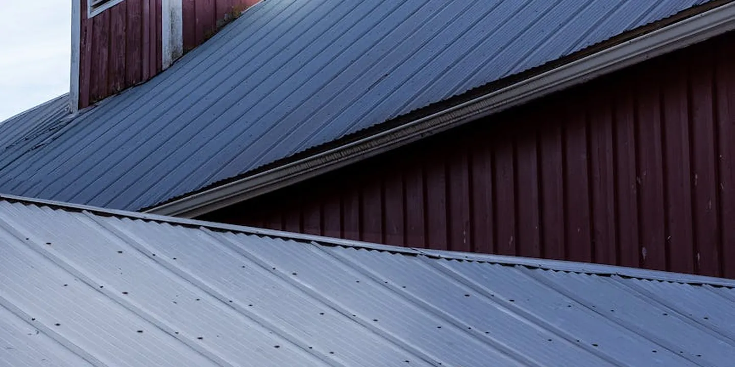 Metal standing-seam roof with intersecting planes on a barn-style building.