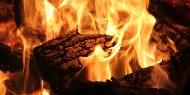 Close-up of bright flames and burning logs inside a fireplace.
